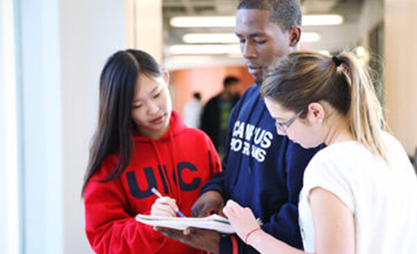 three people looking at a book