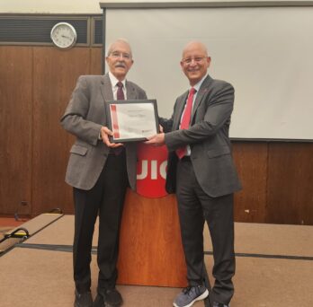 Philip Clifford (left) is presented with a certificate from the UIC College of Applied Health Sciences by Carlos Crespo at AHS Research Day 2023.
                  