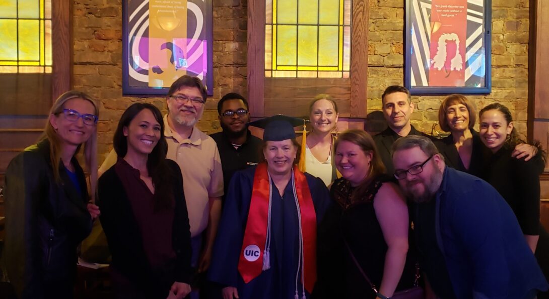 Noreen Chap wears her commencement regalia and is surrounded by a group of colleagues and friends.