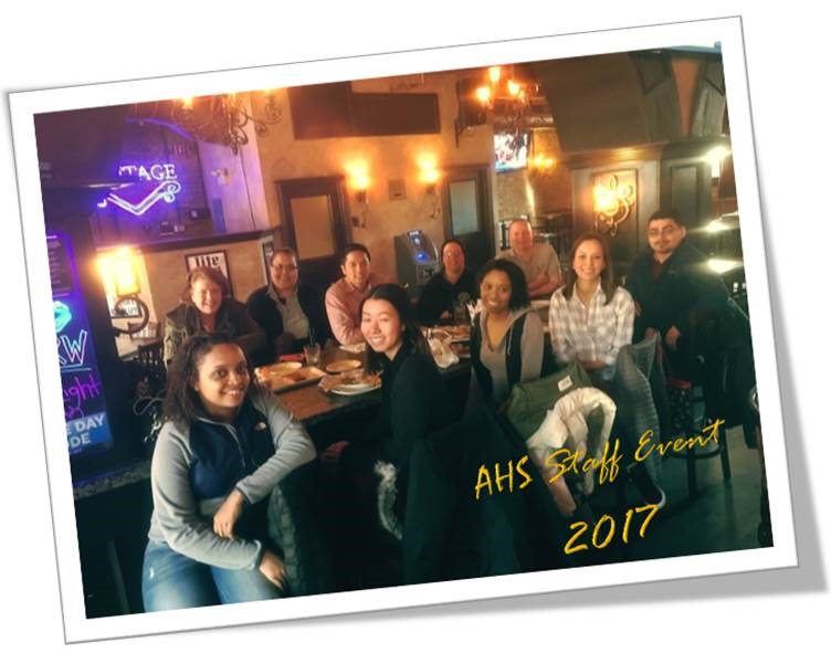 A group of AHS staff members sitting down around a rectangular dining table