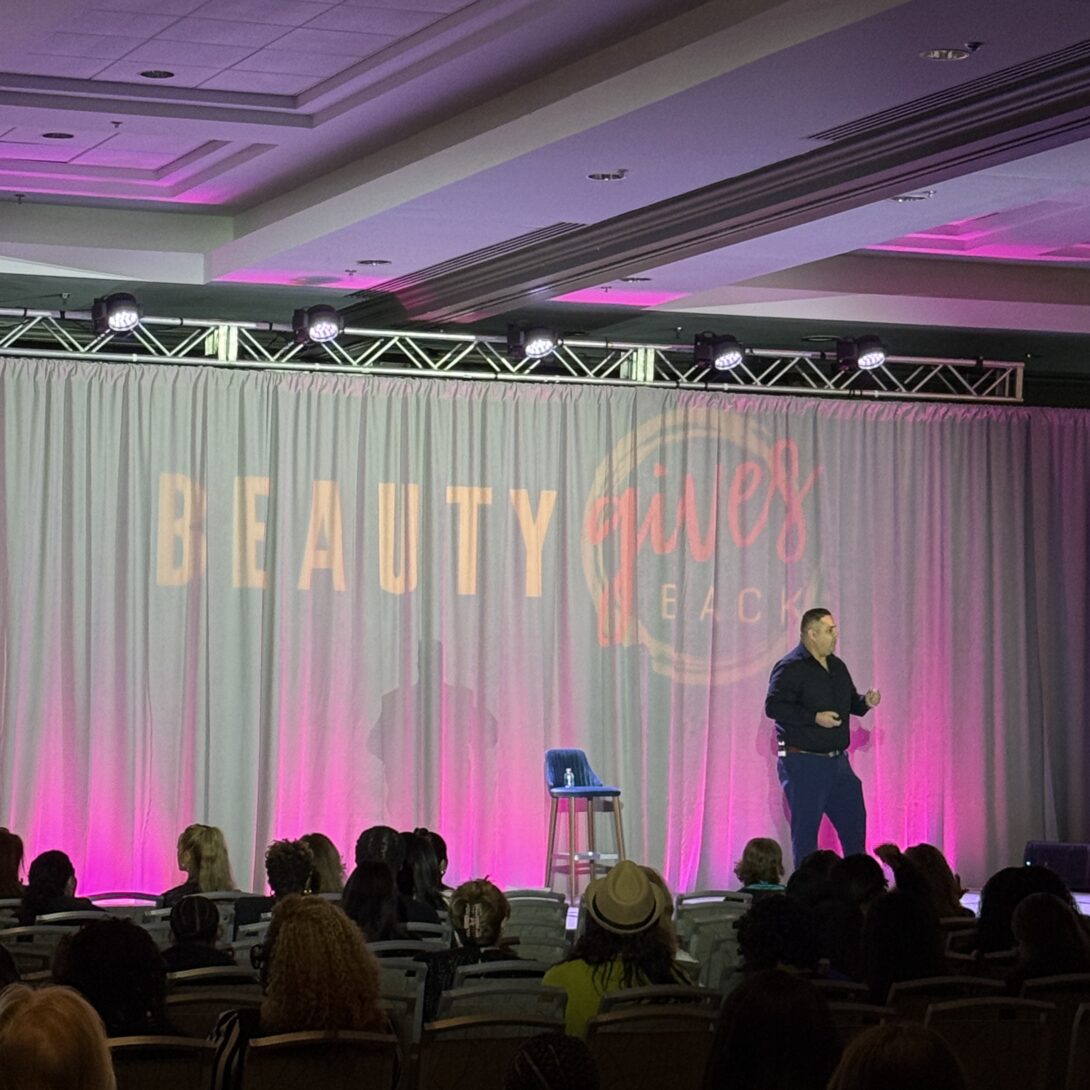 David Camacho presenting on stage at the Pink Pewter Foundation's 2025 Beauty Gives Back.