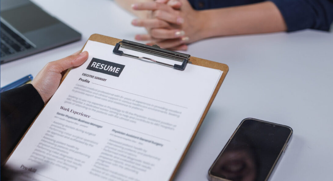 close up of 2 people sitting at a desk reviewing a resume