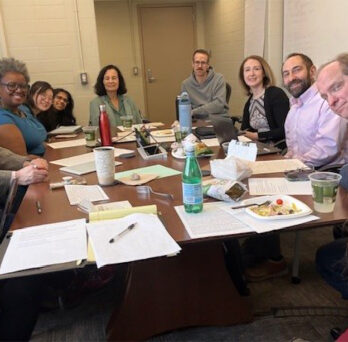People sitting around a conference table discussing a grant proposal
                  