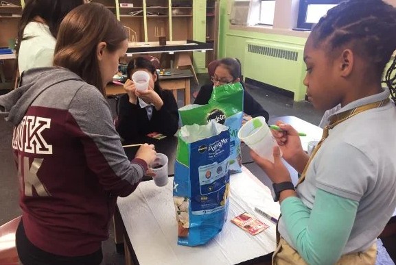 Julie Niewiadomska helping middle school student with potting soil