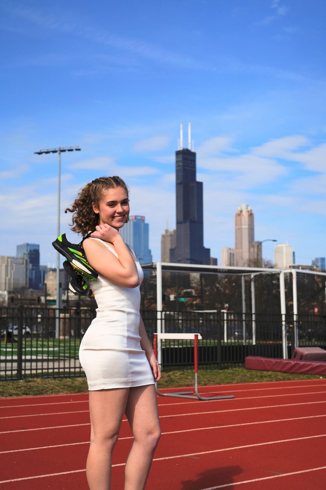 Lia Skoufos ’23 BS KINES standing on a running track with the Chicago skyline in the background