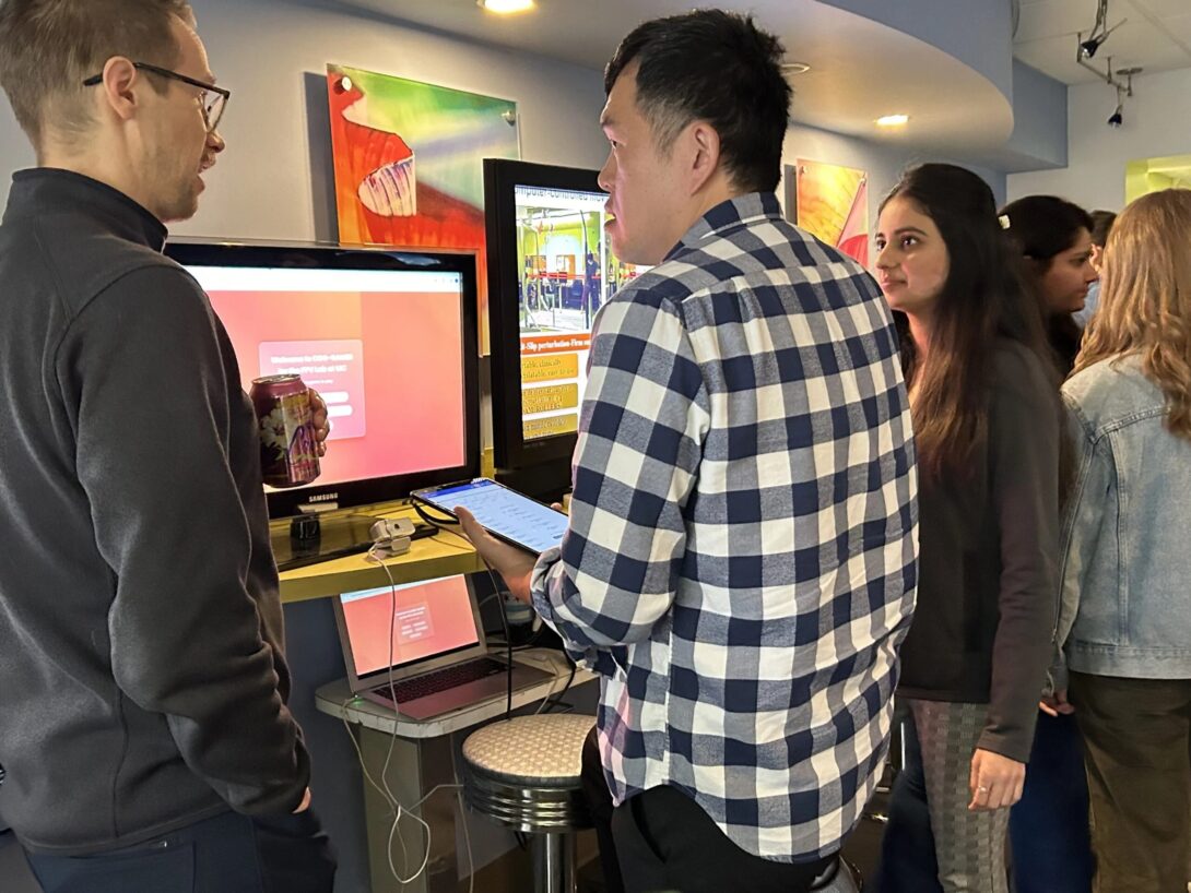 A group of AHS students and researchers gather around a screens to view demonstration.