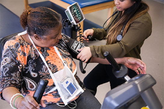 Woman putting blood pressure cuff on another woman's arm