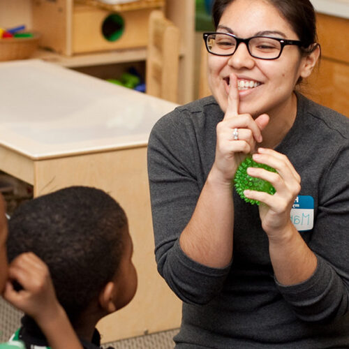 woman with finger at her lips to silence children