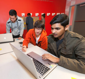 Three men looking at a laptop