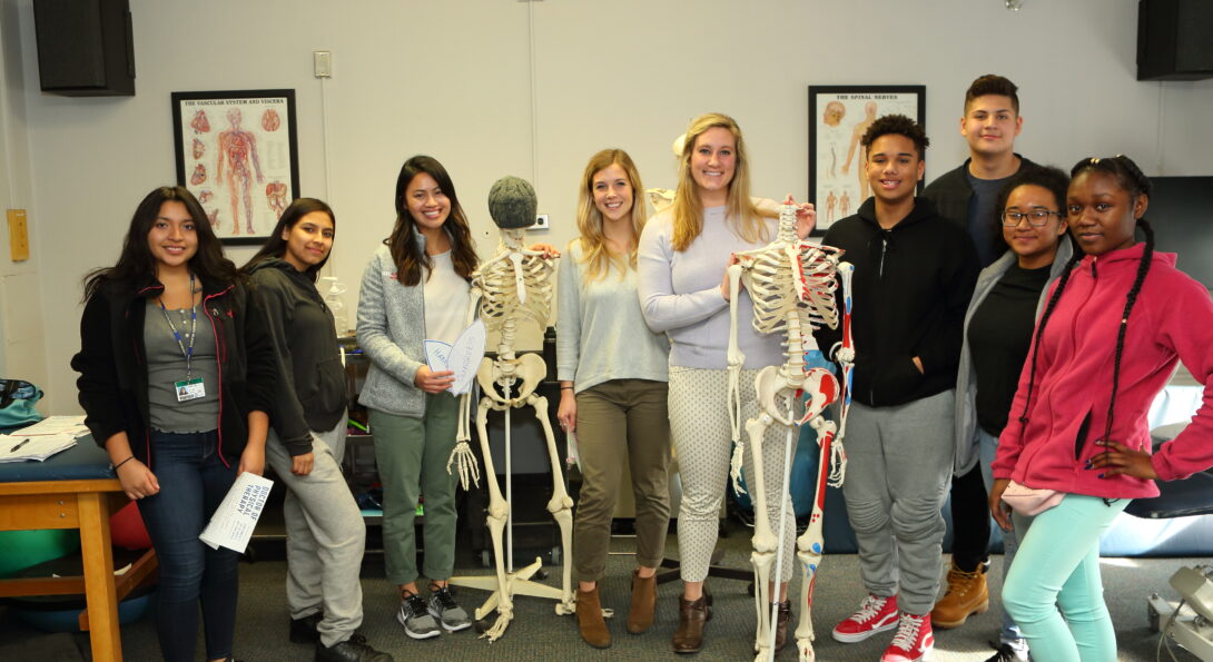 Clemente high school students and AHS intructors pose with two human skeleton models.