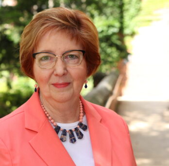 Margret Amatayakul head shot with greenery in the background
                  