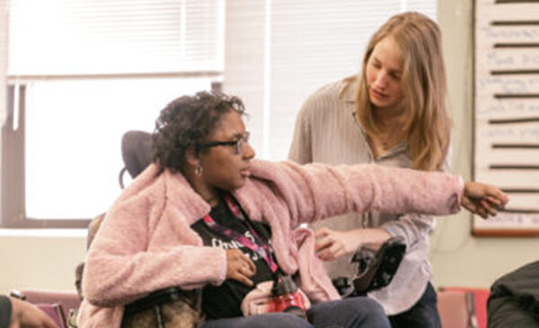 Woman helping another woman in wheelchair with her jacket