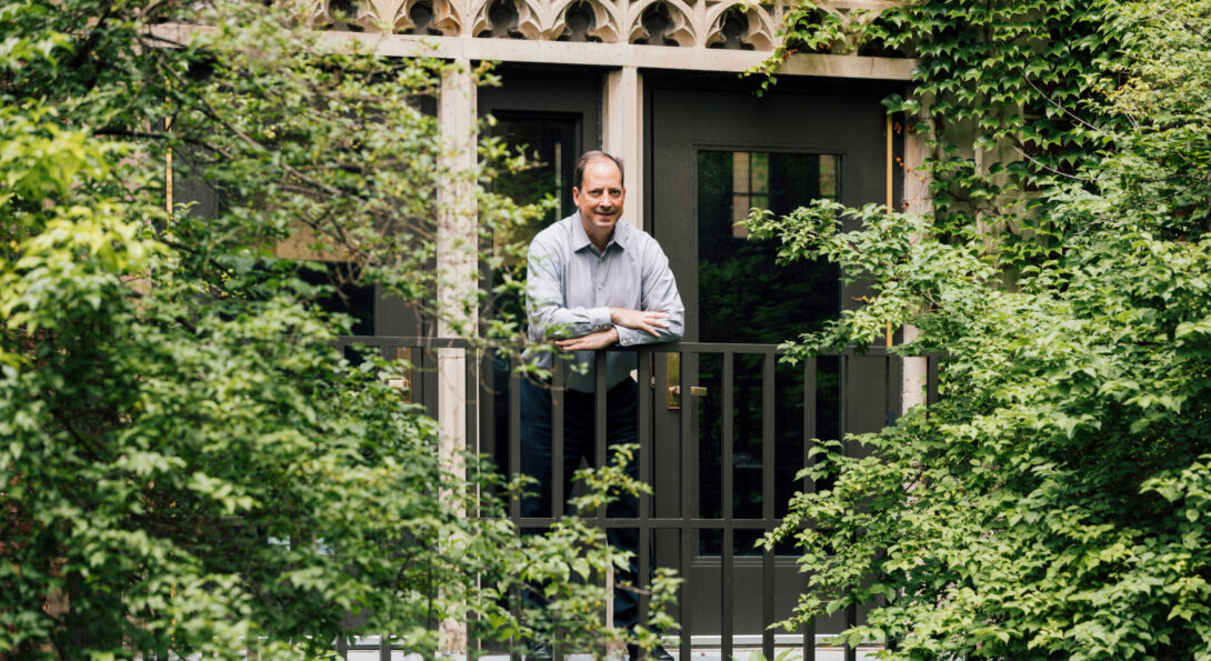 David Scalzitti stands on an elevated balcony surrounded by green treeas and schrubs