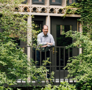 David Scalzitti stands on an elevated balcony surrounded by green treeas and schrubs
                  