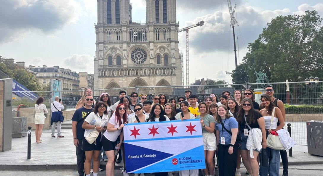 A group of UIC students stand in front of Notre Dame holding a UIC Global Engagement banner