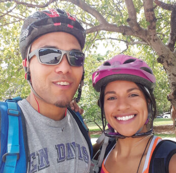 Austin Robinson and Sofia Sanchez pose for a photo with bicycle helmets on
                  