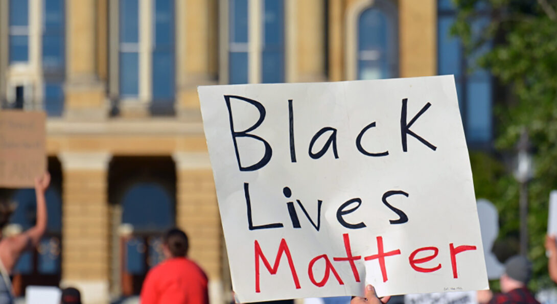 Black Lives Matter sign prominent in front of a crowd