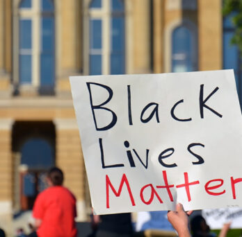 Black Lives Matter sign prominent in front of a crowd
                  