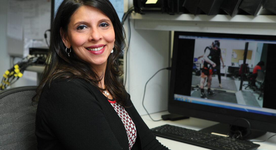 Tanvi Bhatt sitting on desk with computer screen in background