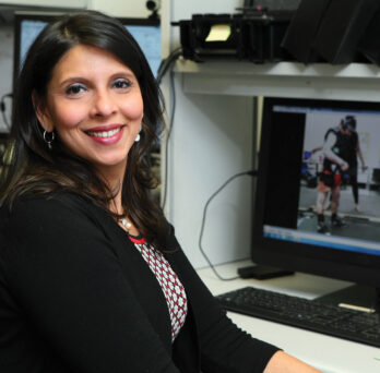 Tanvi Bhatt sitting on desk with computer screen in background
                  