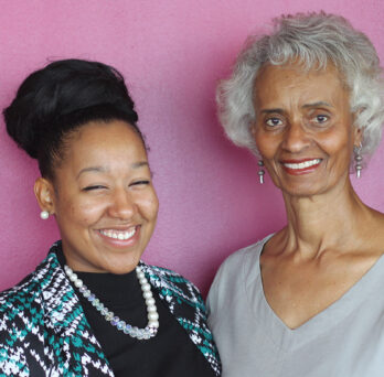 Briana Bonner and Winifred Scott standing in front of a bright pink background
                  