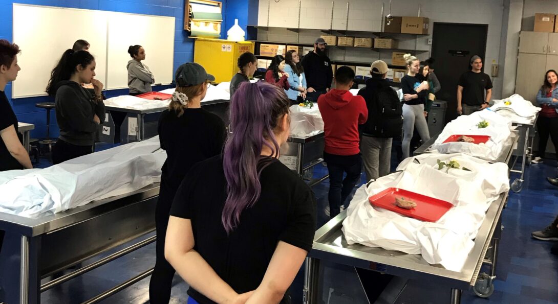 Students stand silently next to cadavers during the ceremony