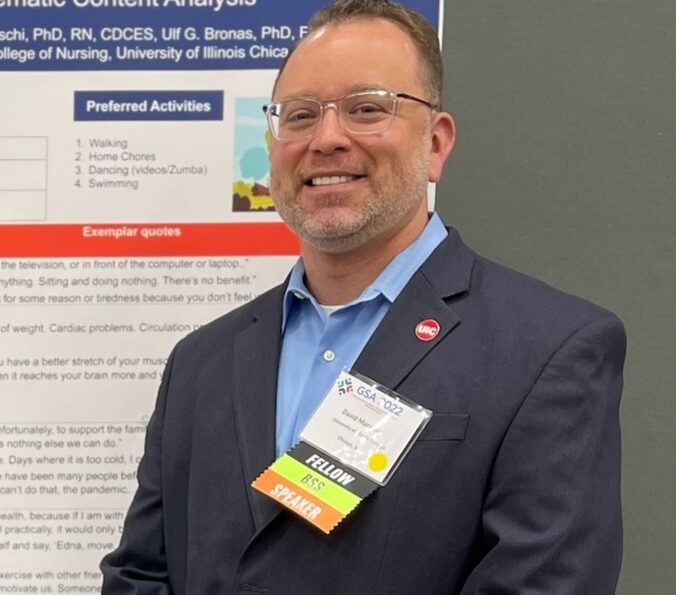 David Marquez stands next to a research poster