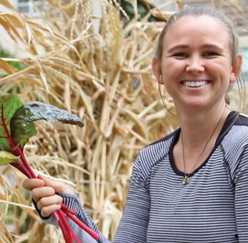 Woman holding a bunch of freshly-picked leafy greens
                  