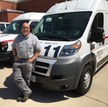 Glenn Hemann leans on an ATU mobile unit which is parked in a parking lot
                  