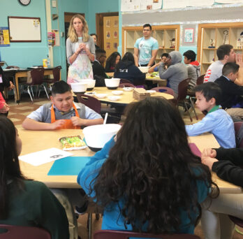 UIC clinical instructor Lindsey Strieter (center) talks to a group of Altus Academy students during a lesson on breakfast in the UIC Health and Wellness Academy.
                  