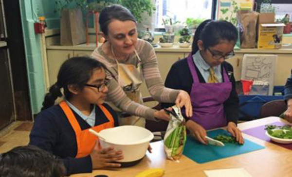 AHS alumna Michelle Reich helps middle school students make a breakfast smoothie during the UIC Health and Wellness Academy