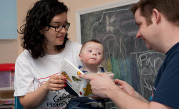 Two people reading to a baby