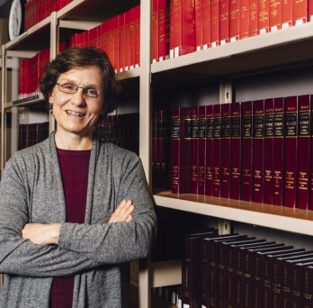 Susan Kahan stands in front of a bookcase filled with law books
                  