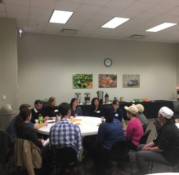 Small group discussions with nutrition and medical students, and participants in the Chicago Community Kitchens program, which trains unemployed and underemployed individuals to work in food service around a circular table.
                  