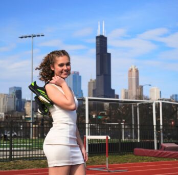 Lia Skoufos ’23 BS KINES standing on a running track with the Chicago skyline in the background
                  