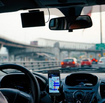 A photo from a car backseat perspective that shows a ride share drive behind the wheel of a car
                  