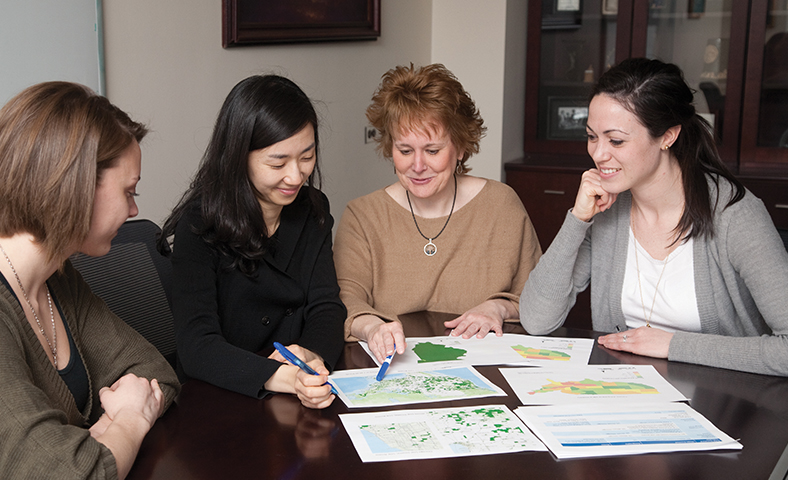 Jenna Heffron stitting with a group at a table looking at papers