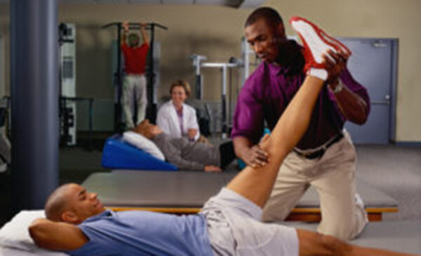 A physical therapist manipulates a client's knee