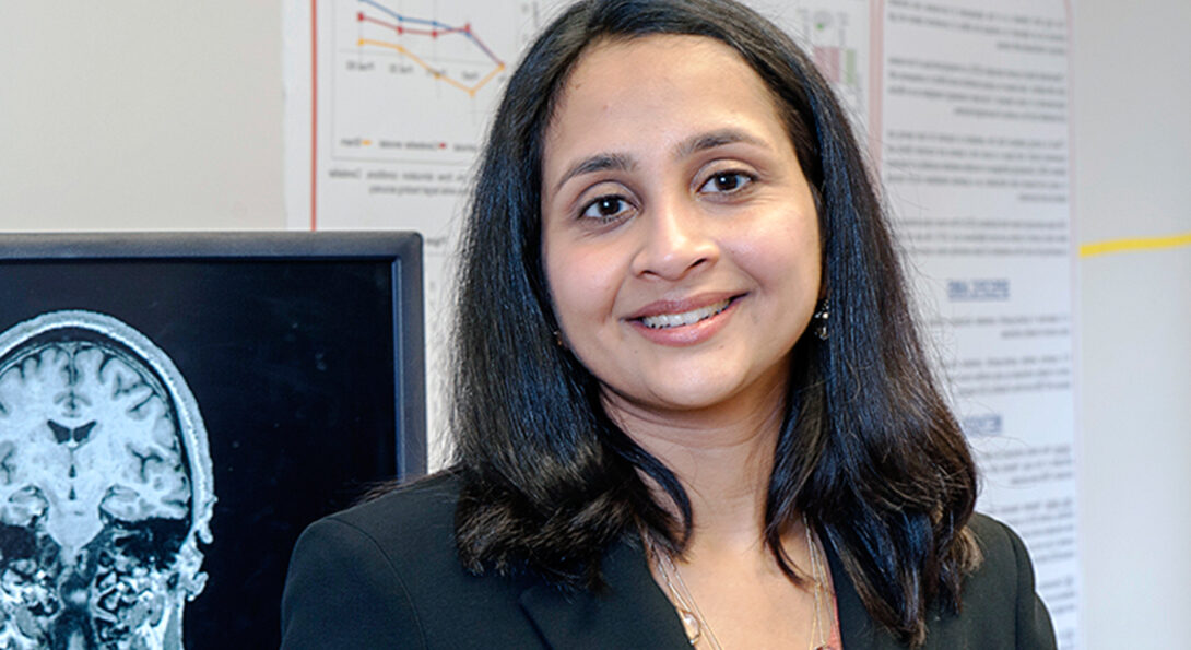 Sangeetha Madhavan in front of Brain Plasticity Lab equipment