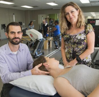 Adam Wielechowski and Deb Davey with a person on a mat table
                  