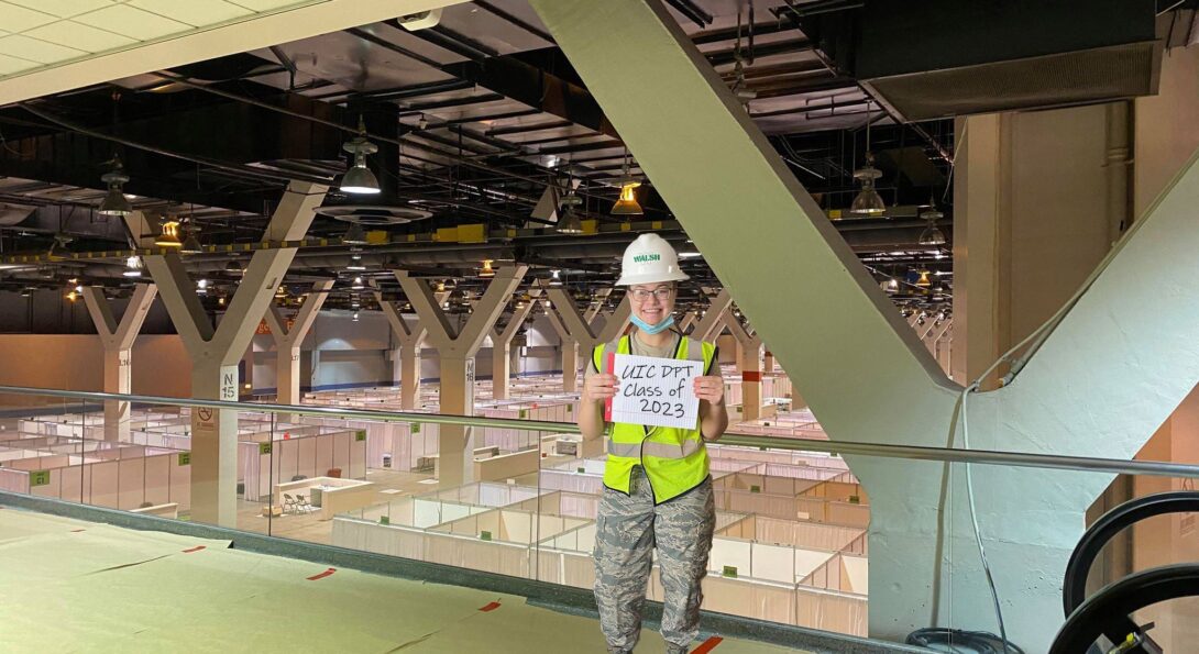 Cassandra Hall inside the McCormick Place Convention Center she helped transform into a temporary hospital for 3,000 COVID-19 patients holding a sign tha reads 