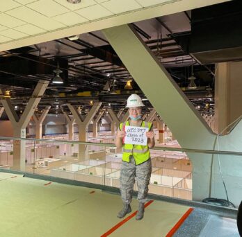 Cassandra Hall inside the McCormick Place Convention Center she helped transform into a temporary hospital for 3,000 COVID-19 patients holding a sign tha reads 