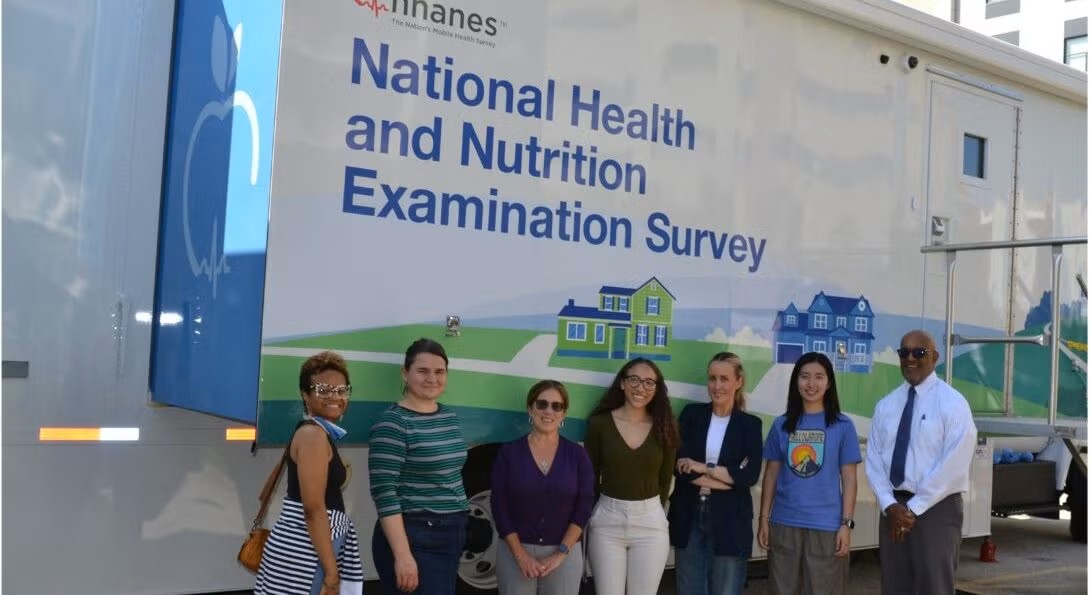 AHS and SPH faculty and staff stand in front of the NHANES mobile examination center.