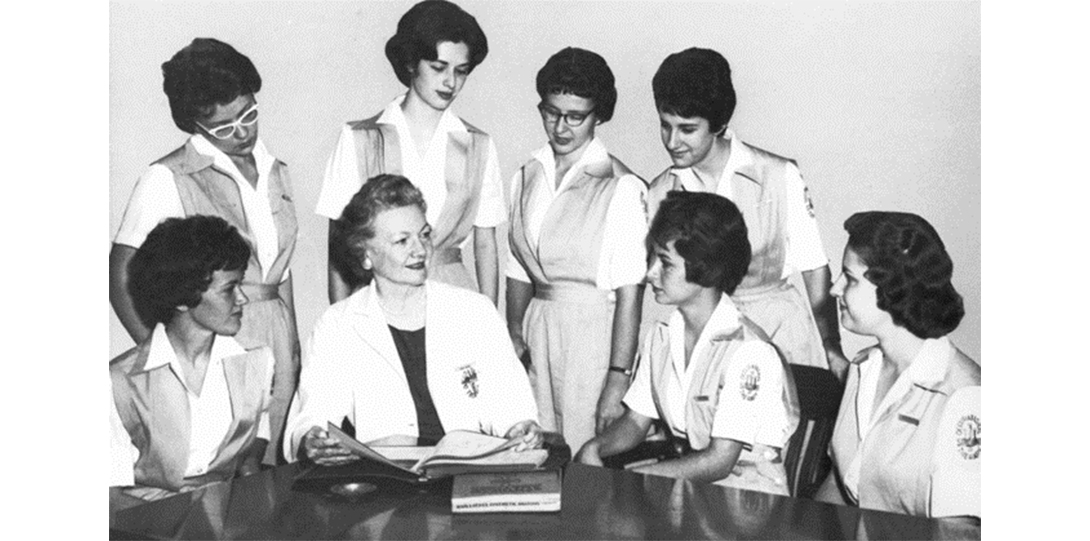 A black and white photo of Beatrice Wade surrounded by UIC OT students, dated 1961.