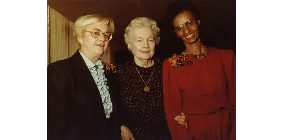 A group of three women standing and smiling at the camera.