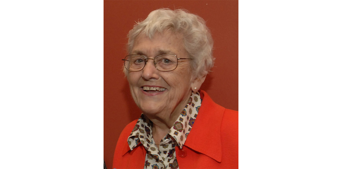A woman with glasses wearing a red top smiling at the camera