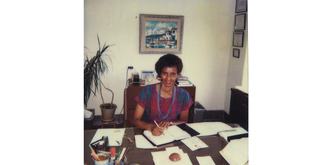 A woman sitting at a desk covered in papers