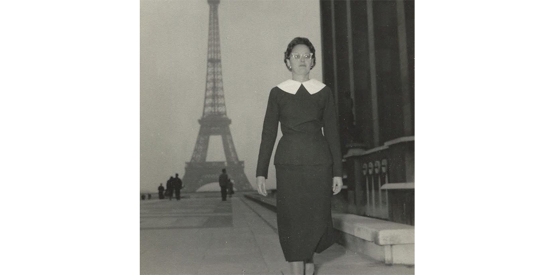 Black and white photo of a woman walking down a street with the eiffel tower in the background