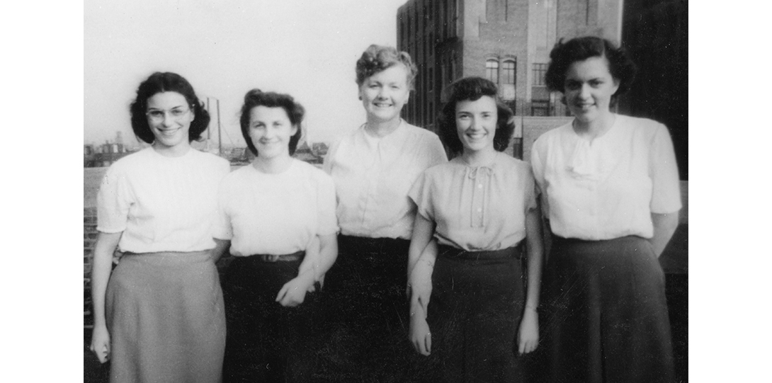 black and white photo of 5 women standing and smiling at the camera