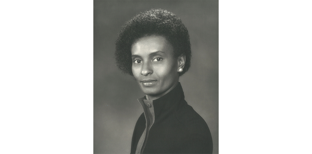 Black and white photo of a woman smiling at the camera.